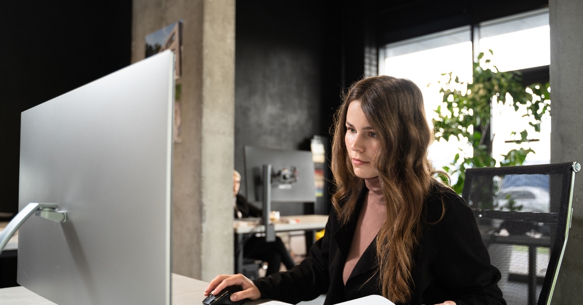 female architect suit with blueprints at table using computer at office