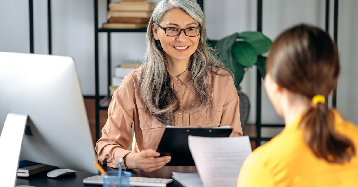 senior manager from hr department holding documents while listening to young female applicant 