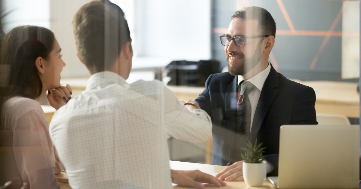 male realtor congratulating young couple 