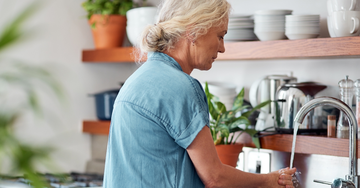 mature woman washing her hands in the kitchen sink