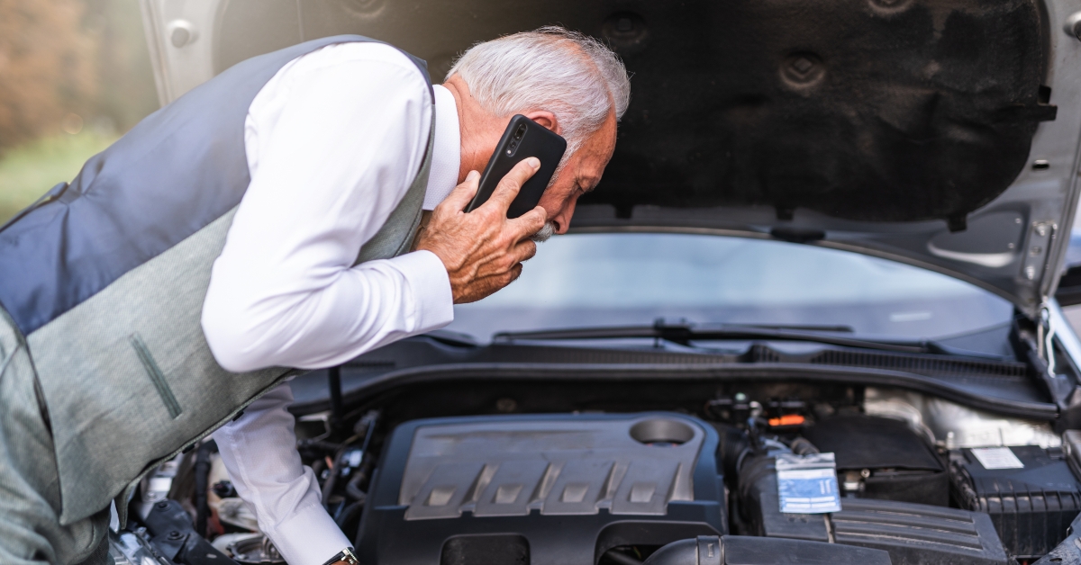 senior man looking at car engine