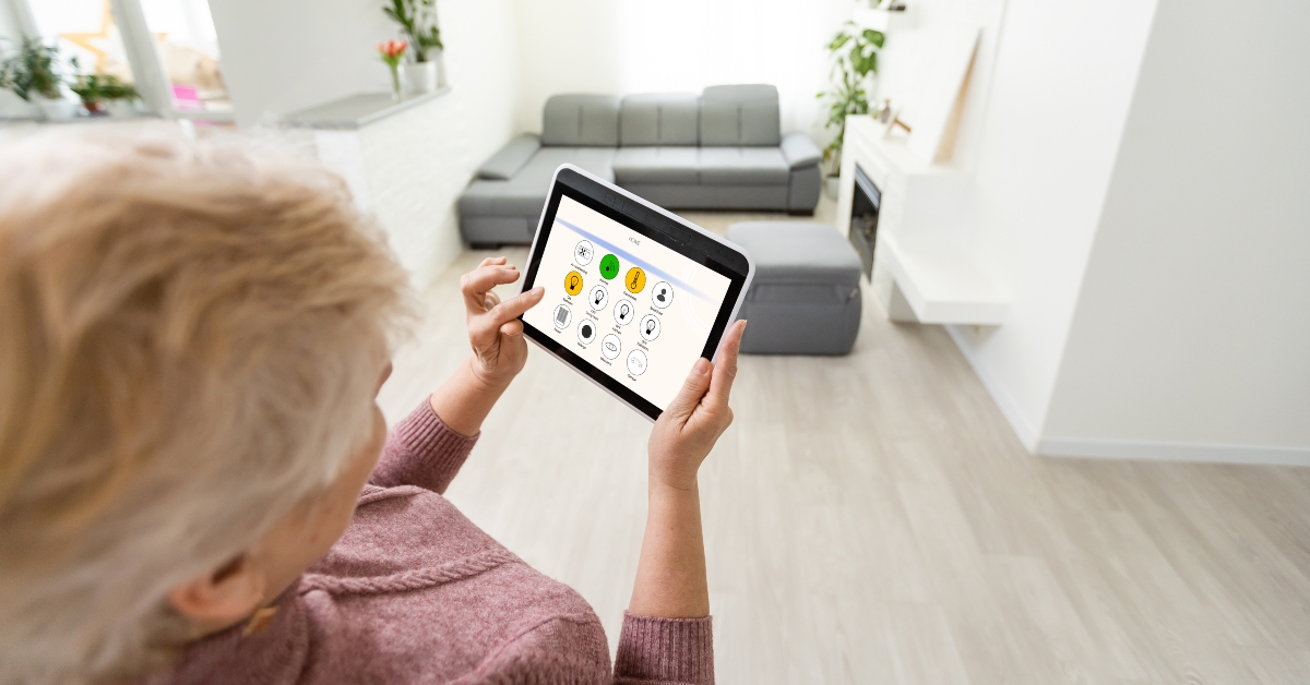 senior woman at home standing at kitchen holding digital tablet