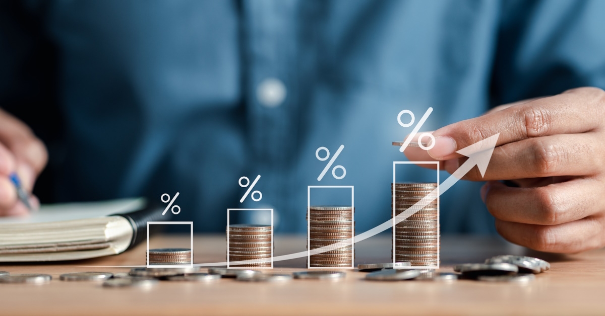 man stacking coins on wooden table with d percentages and graphs showing dividend concept