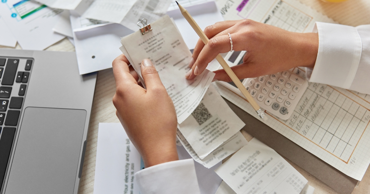 unrecognizable woman holds receipts and pencil 