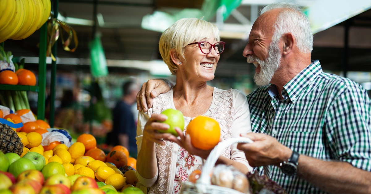 smiling senior couple holding basket with vegetables