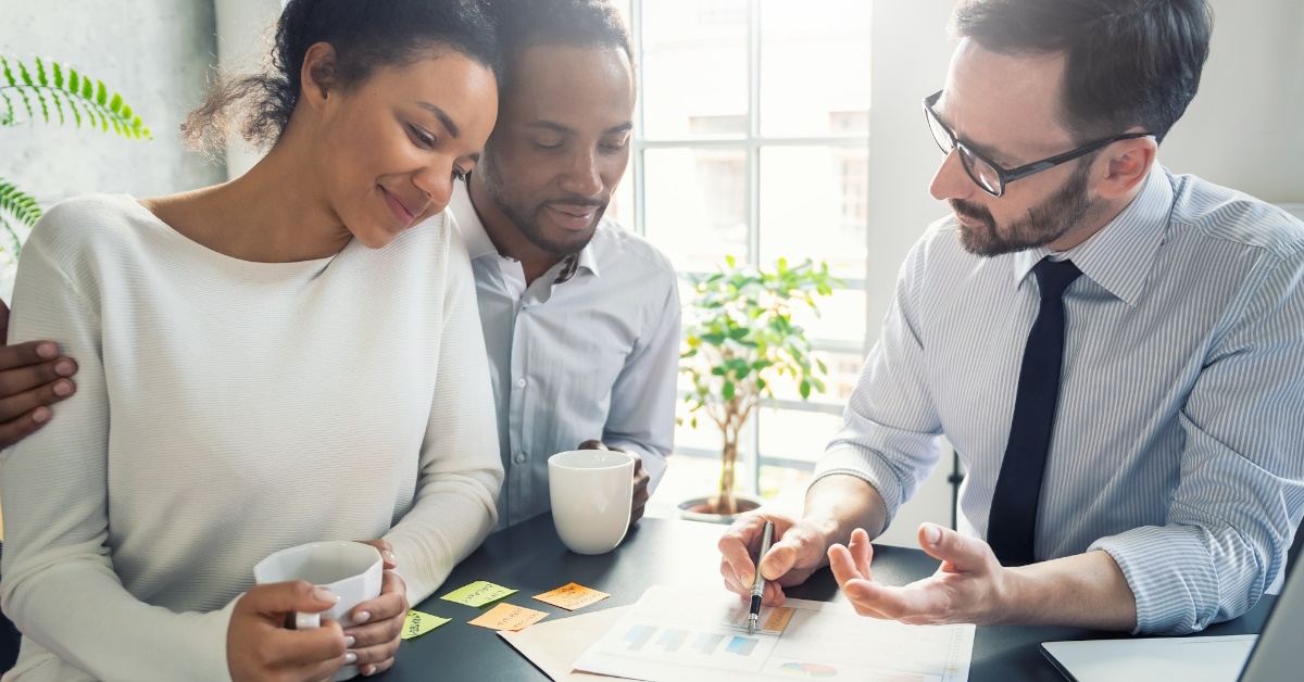 male insurance agent explaining policies to african american couple