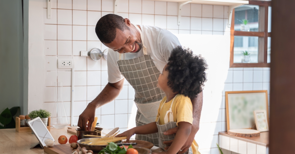 Father and little boy cooking in kitchen at home