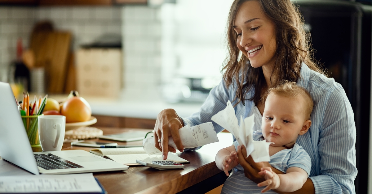 happy mother with baby son calculating bills at home