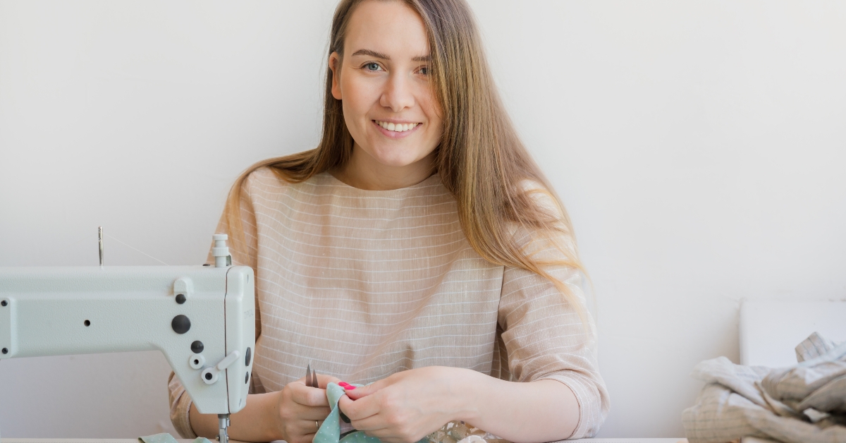 happy seamstress sewing clothes at own atelier