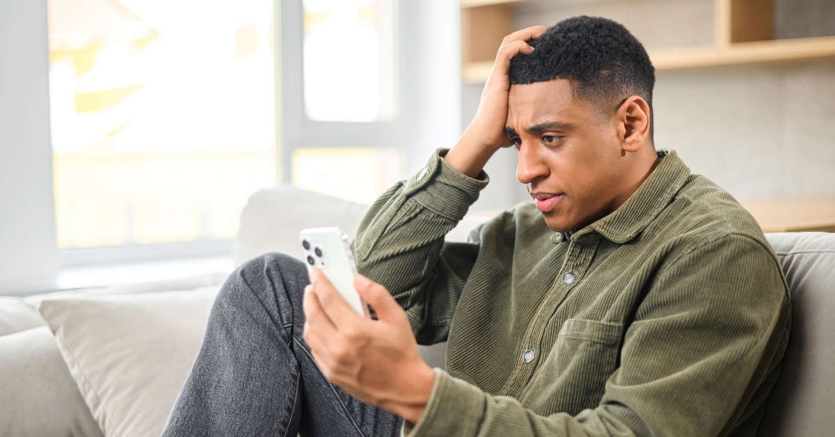 man holding smartphone and sitting on the sofa