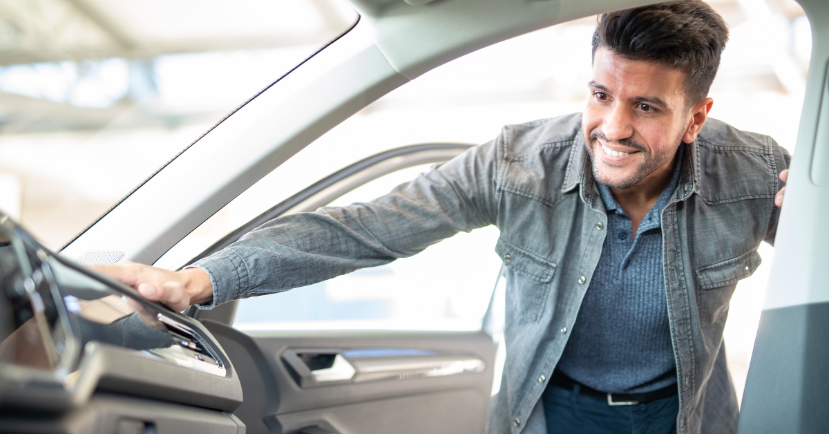 smiling man taking taking look to car in showroom