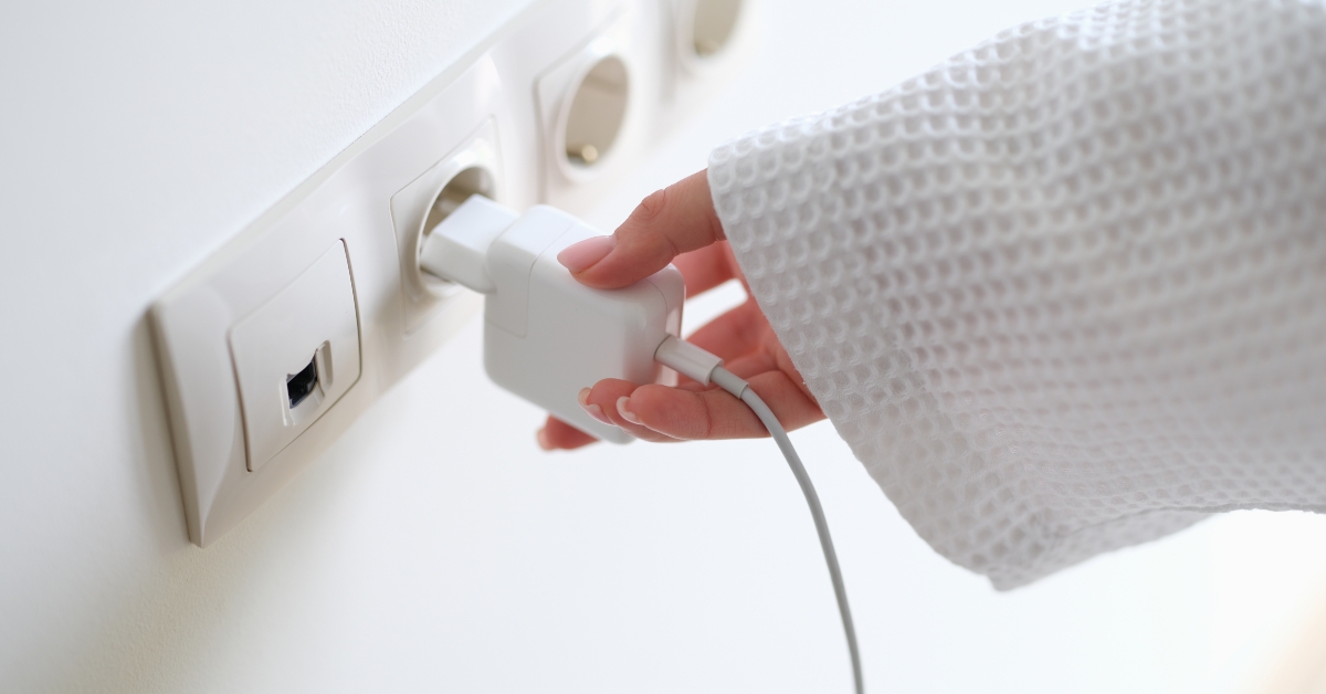 woman in white bathrobe inserting plug into outlet