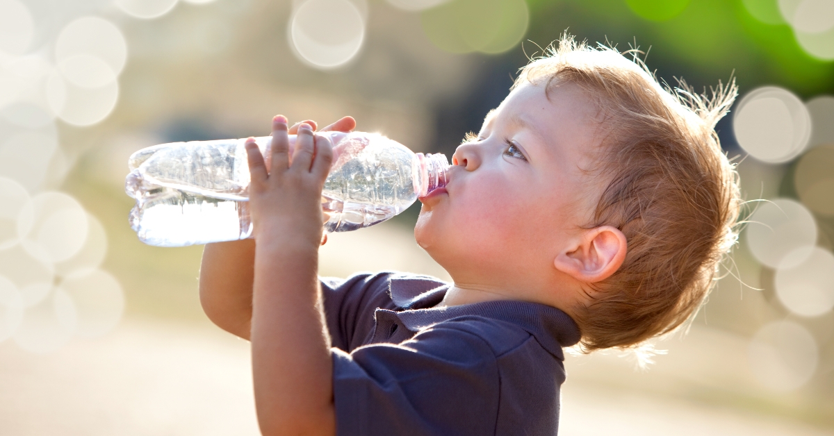 blonde child drinks water outdoor