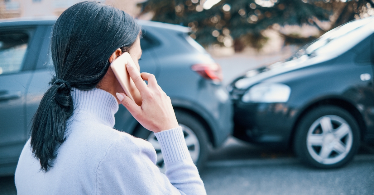 woman calling insurance roadside assistance after car crash