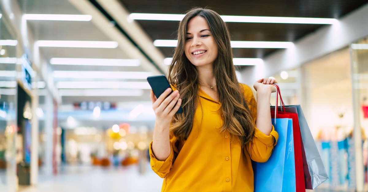 woman with shopping bags is using smartphone in the mall