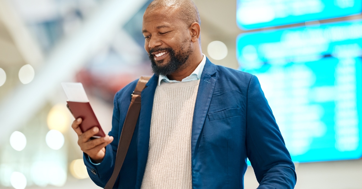 african american man standing in airport lounge using smartphone