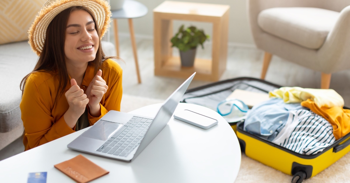 woman excited while booking trip using laptop