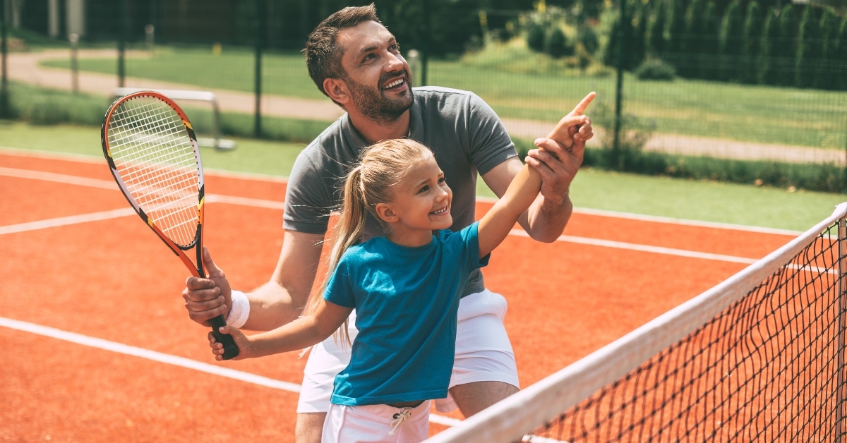 A father and daughter playing tennis