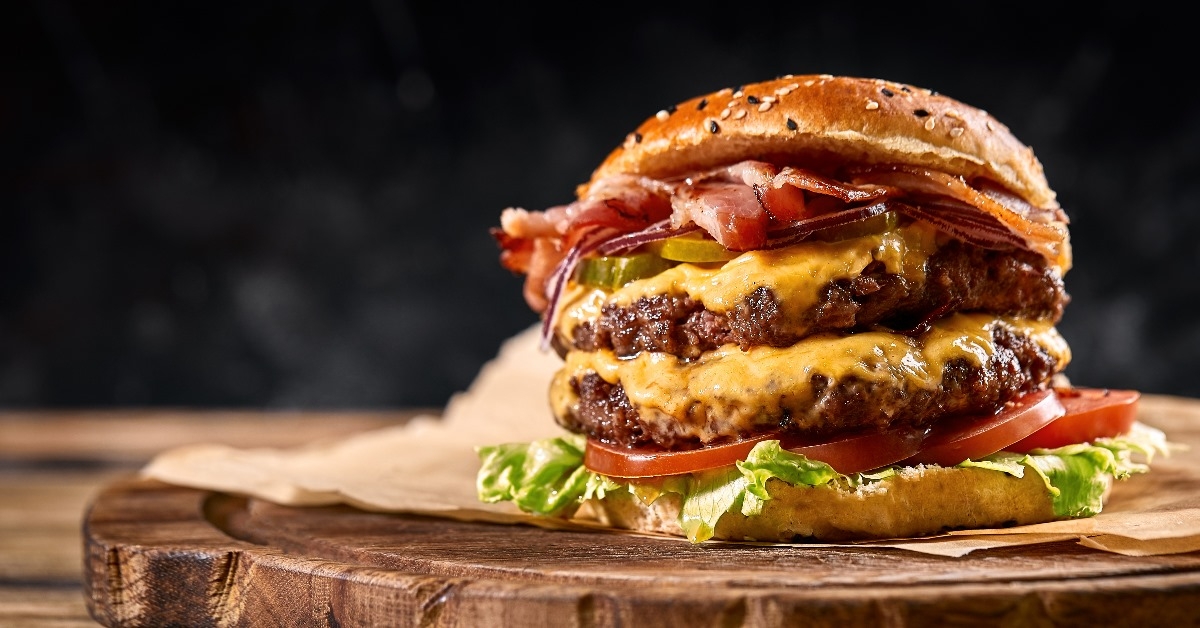 juicy american burger with cheese, two beef patties, lettuce and tomato slices