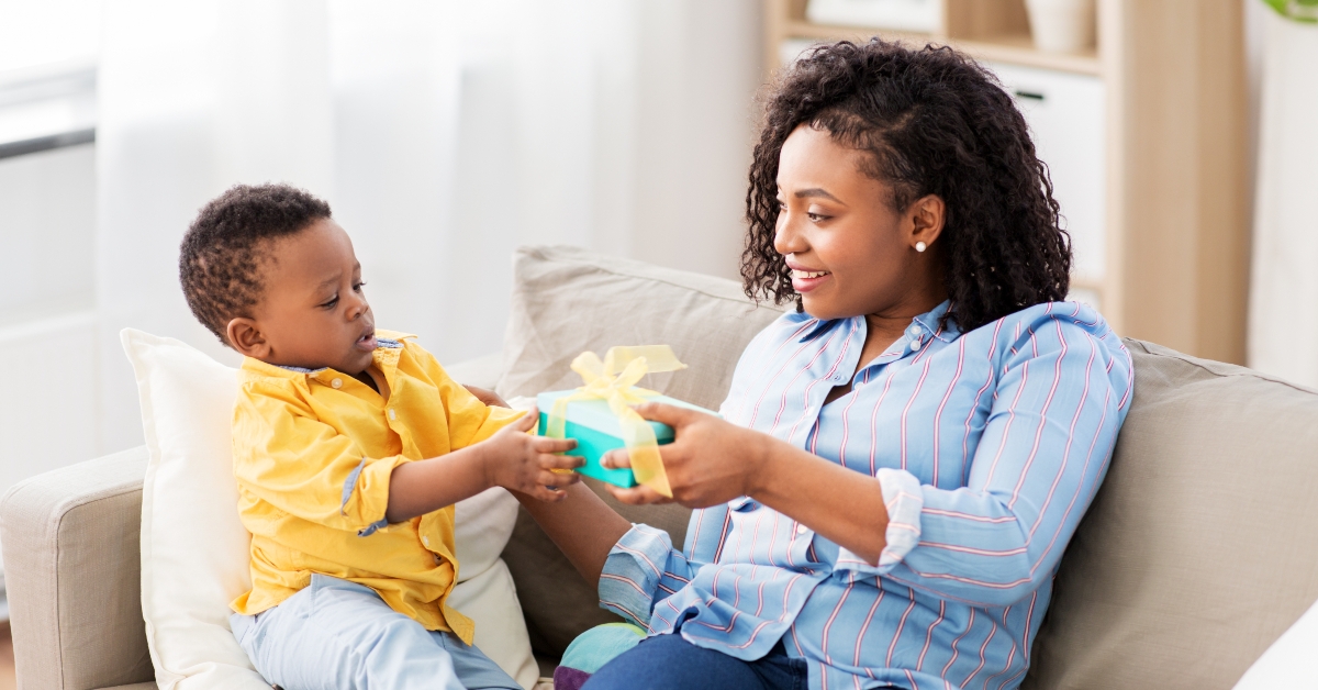 mother giving present to her baby son at home