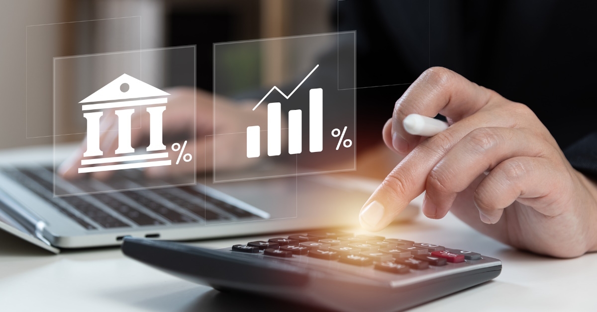 woman sitting on table using laptop and calculator to calculate interest rate