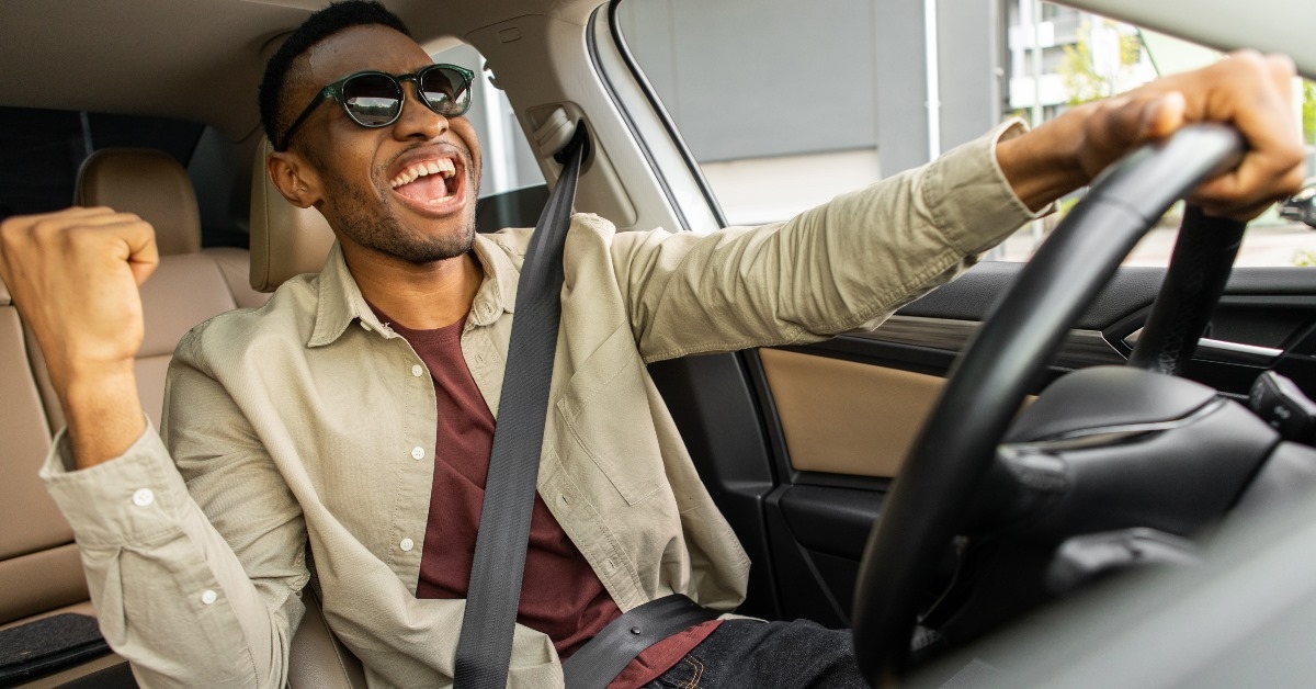 african american man dancing and singing while driving car