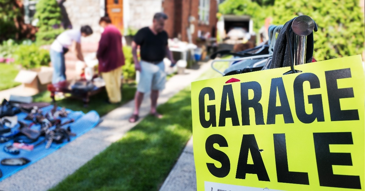 garage sale sign in front of house with shoppers in background
