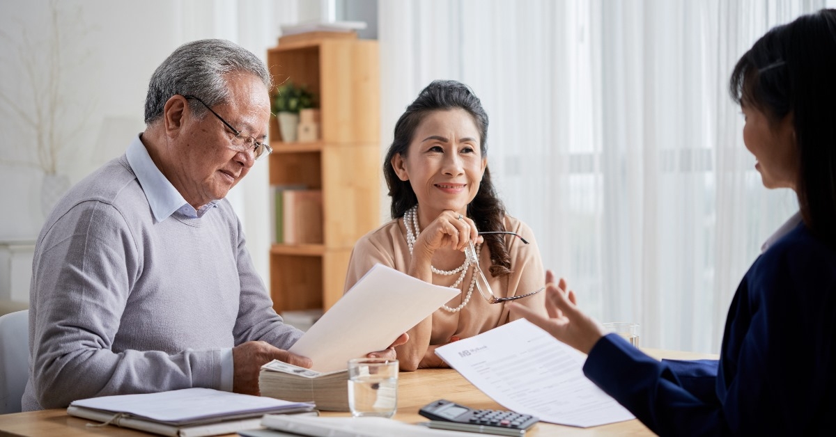 senior couple consulting with estate agent showing terms and policies.