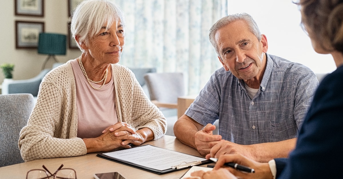 senior couple planning their investments with financial advisor sitting in her office.