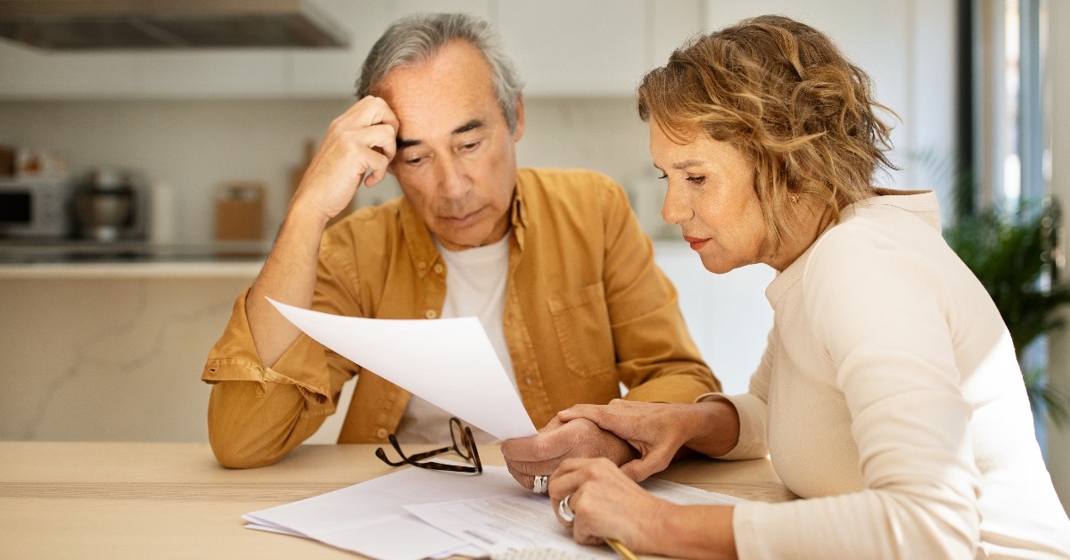 senior couple sitting at table reviewing bills in kitchen