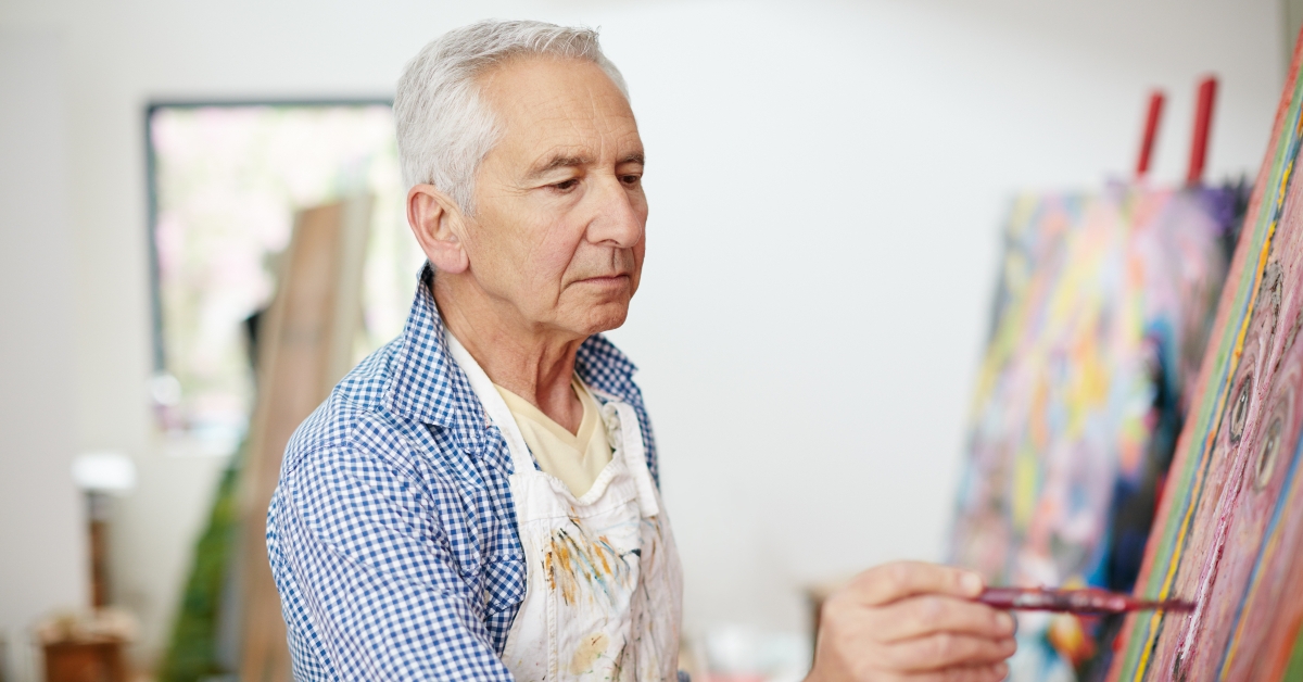 senior man working on a painting at home