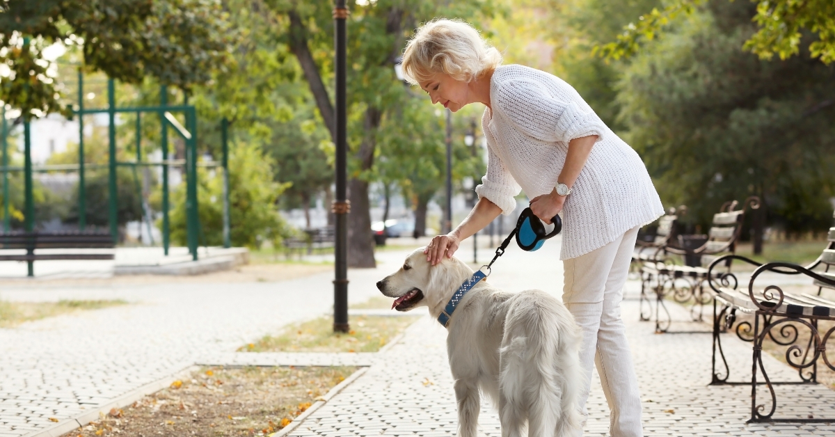 senior woman walking with dog in park