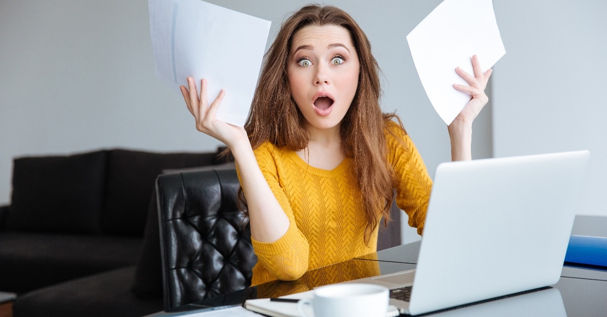 woman covering her face in shock while working at office