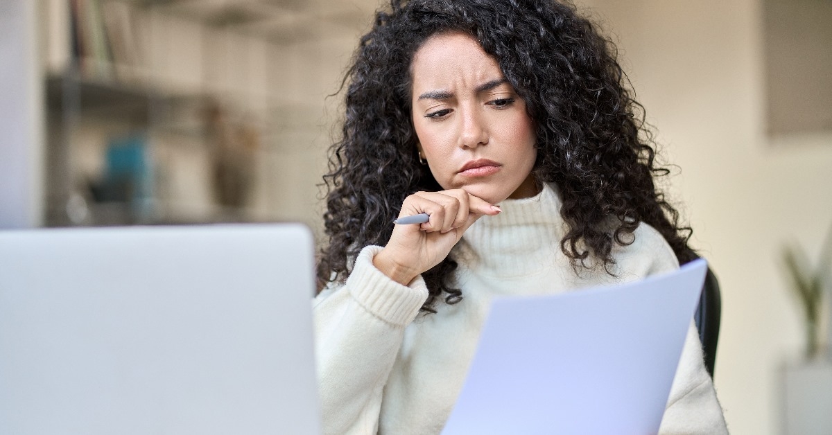 female accountant sitting at office worrying about documents while using laptop 