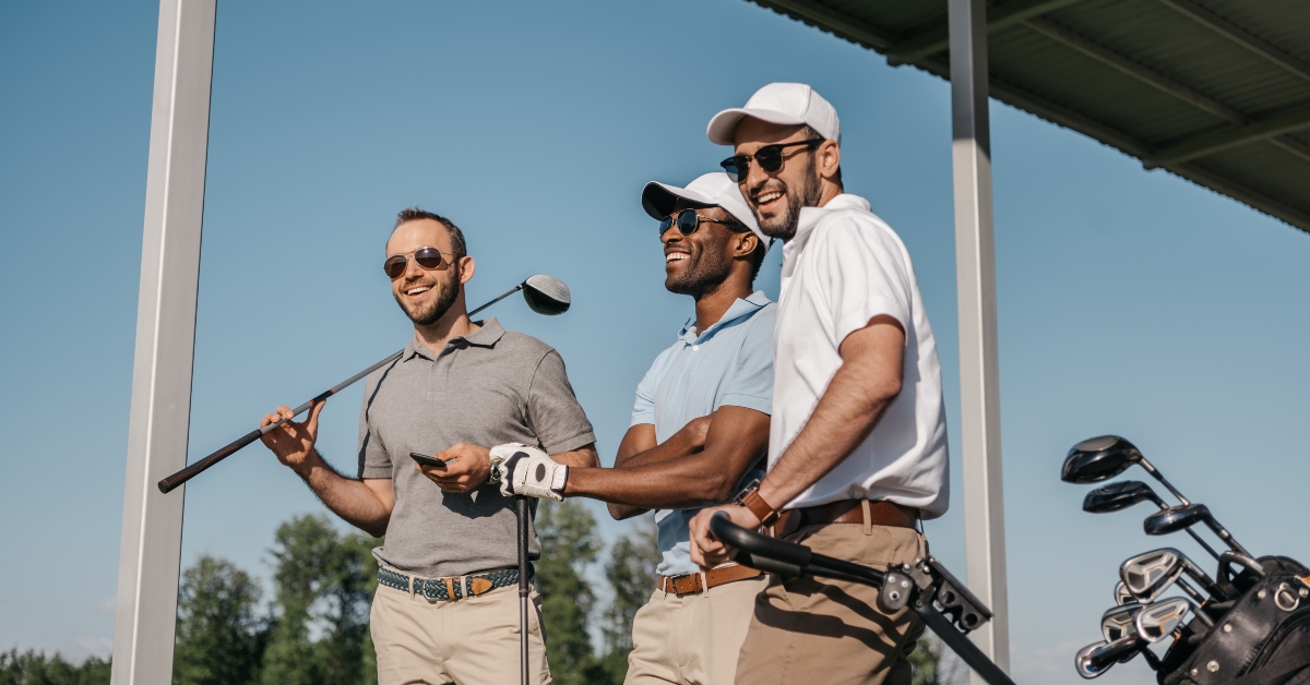 smiling men in sunglasses holding golf clubs outdoors