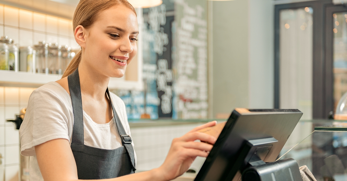 cheerful shop assistant using digital device for payment