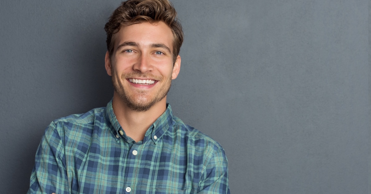 happy handsome man wearing check shirt posing for camera over grey background