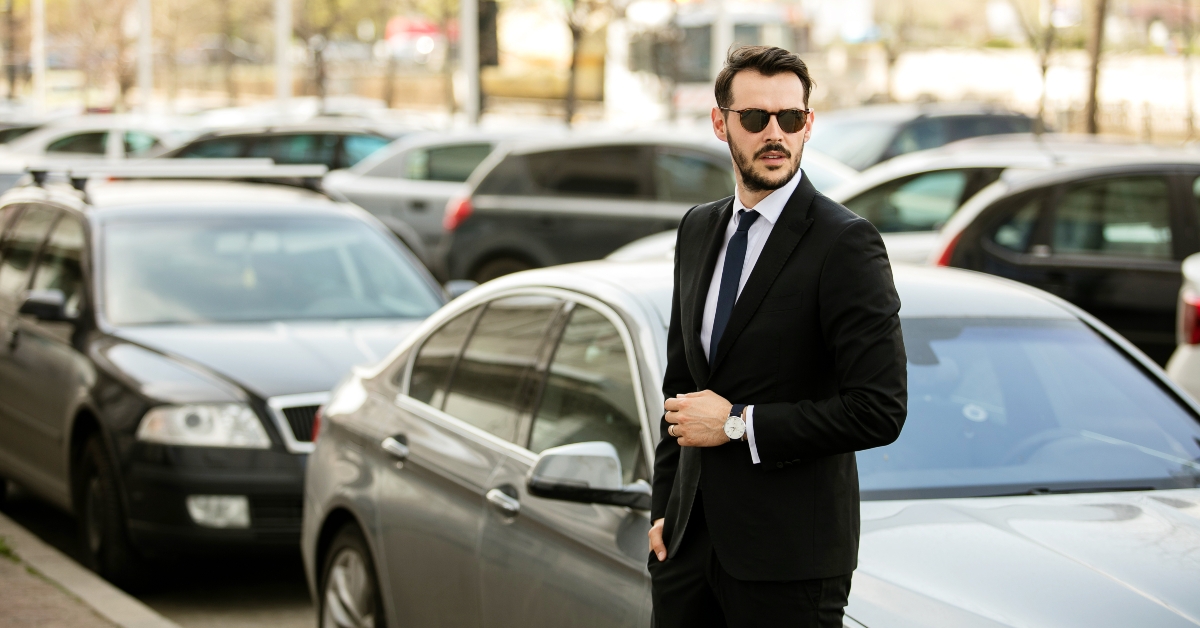 successful and handsome man in suit outside with his expensive car