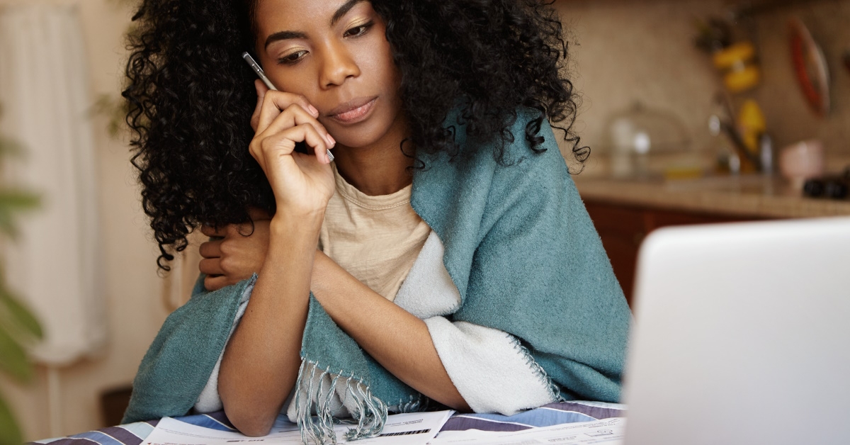 african american woman on call lost in thoughts while reviewing bills