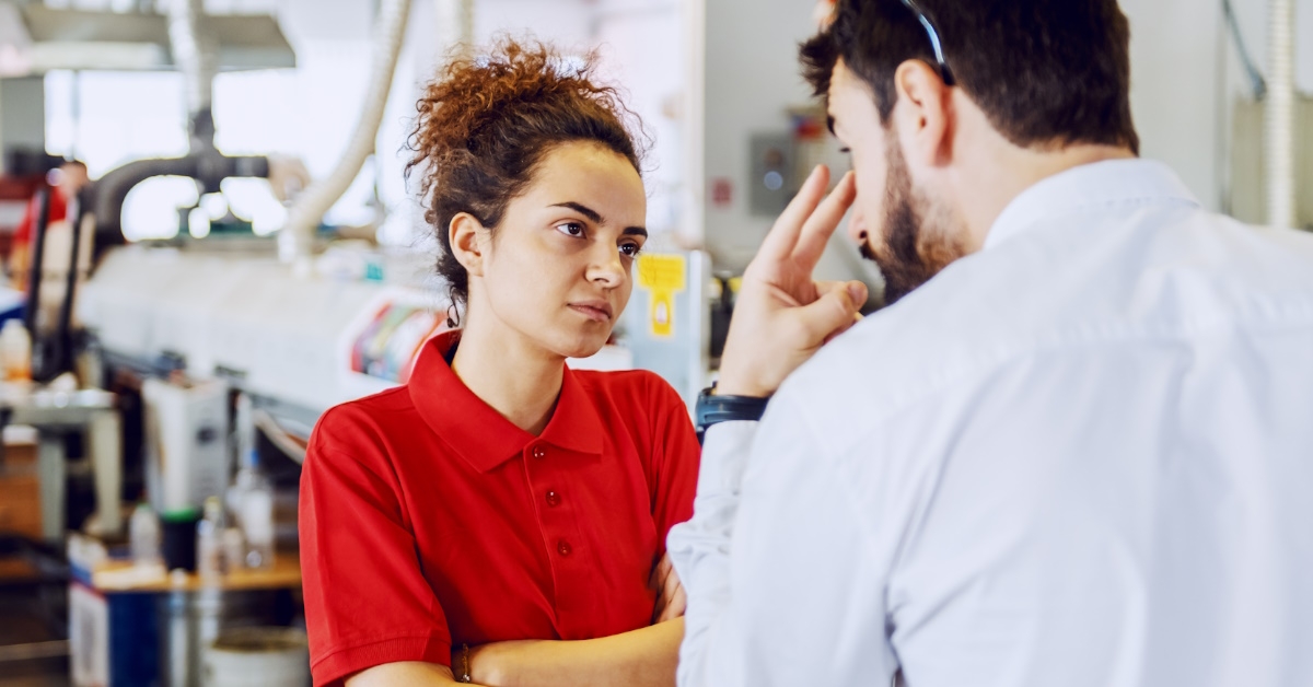 angry male director scolding female technician folding hands at work