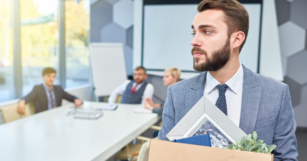 man holding box of personal belongings moving out of his office