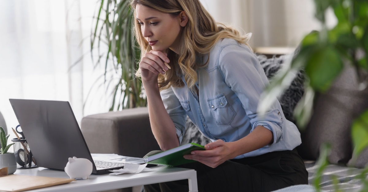 woman sitting on couch using laptop while calculating home expenses