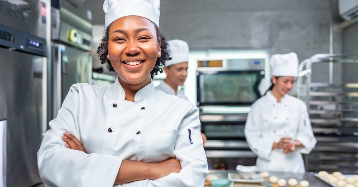 african american female baker folding hands in bakery 