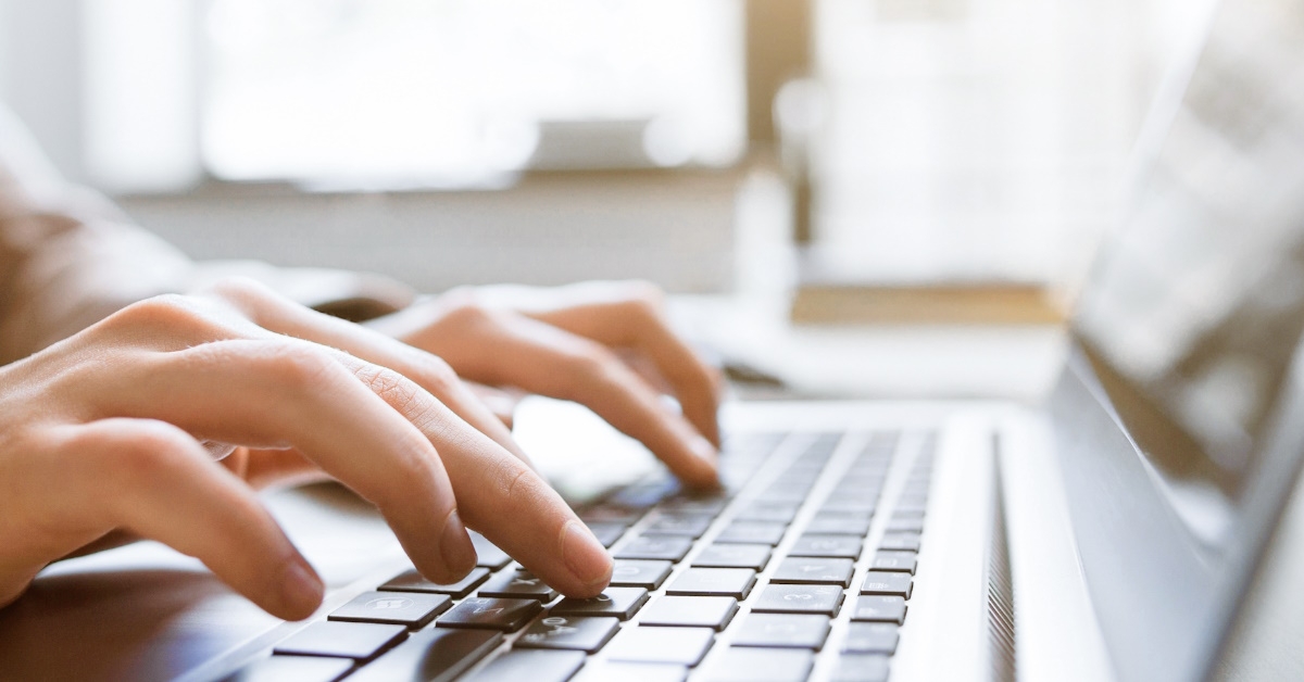 content writer typing on laptop using keyboard