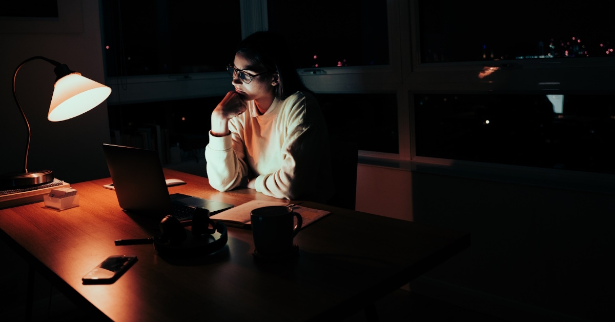 female student sitting at table using laptop for studying late at night
