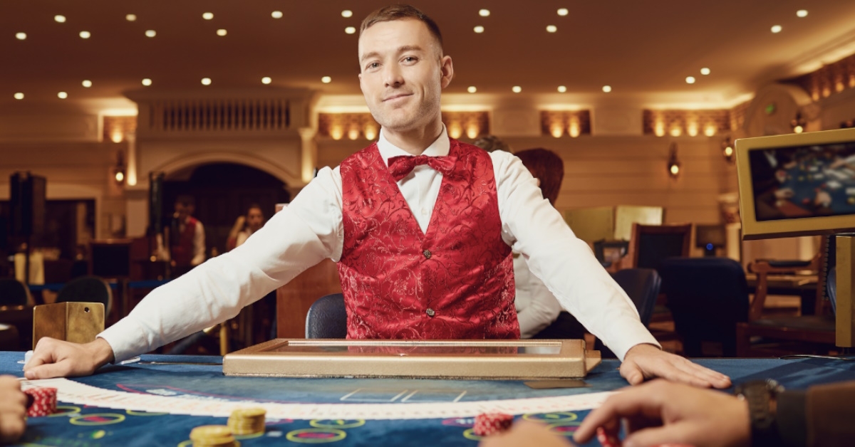 male croupier standing confidently at table in casino