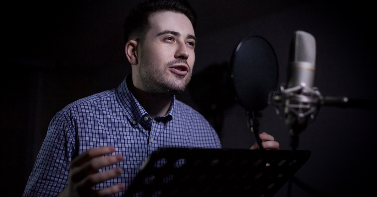 male dubbing actor using microphone to record sounds in studio