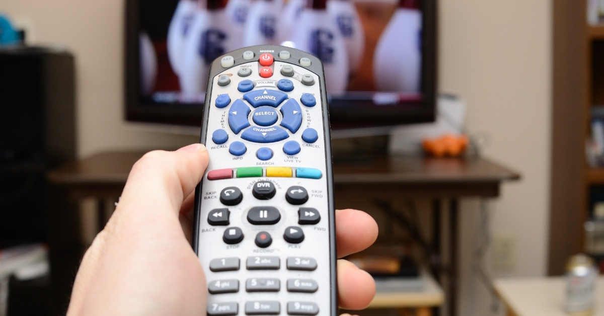 man using tv remote control with tv in background