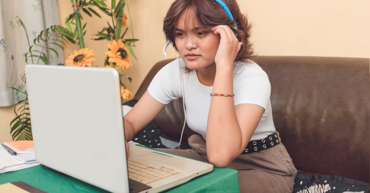 young woman using headphones working on laptop