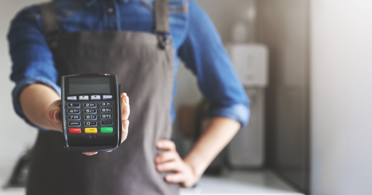 female waitress in apron holding pos terminal in hand at cafe